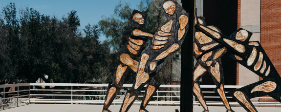Statue showing muscle and bones human figures pushing on both sides of border wall