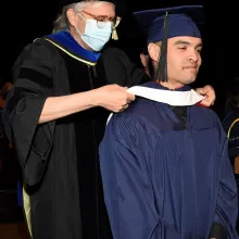 Christopher Mitchell receiving graduation hood